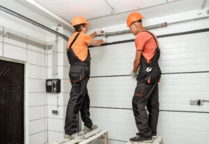 Two technicians replacing commercial garage door system