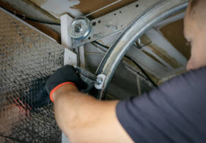 Garage door technician tightening casters on track