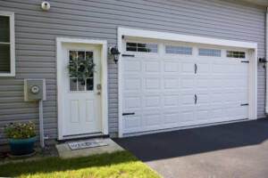 New vinyl garage door with handles and lined by landscaping