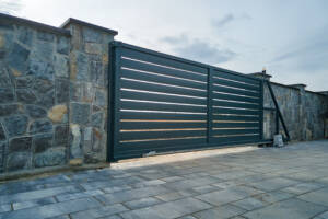 Wide residential security gate on stone wall