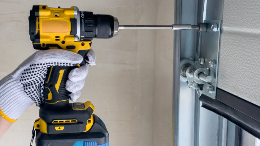 Technician assembling sectional garage door using power drill