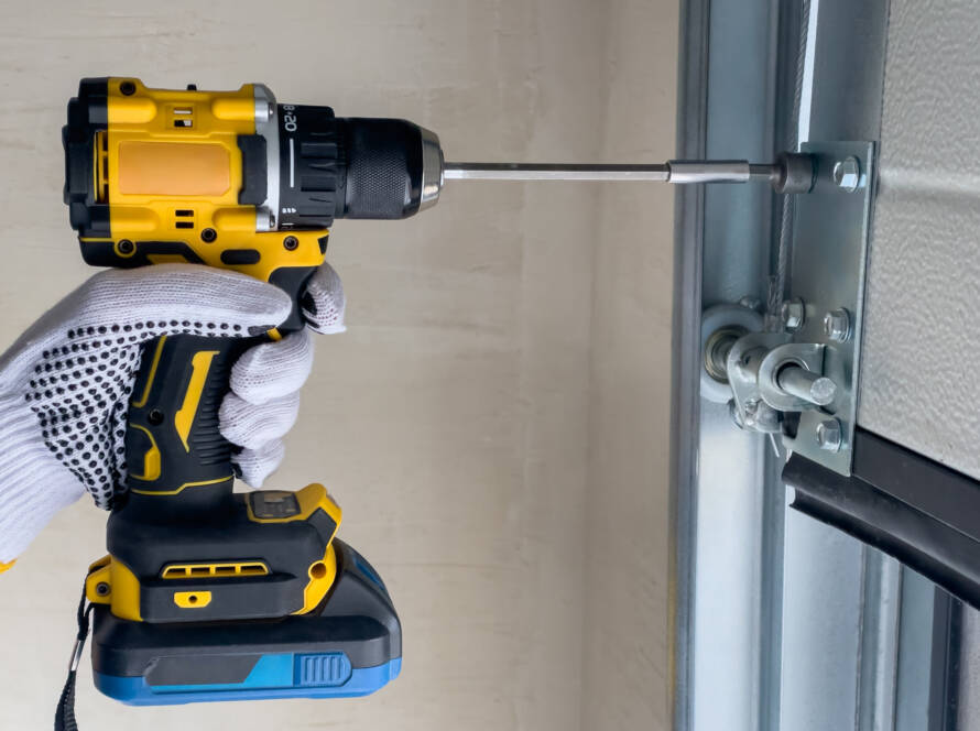 Technician assembling sectional garage door using power drill