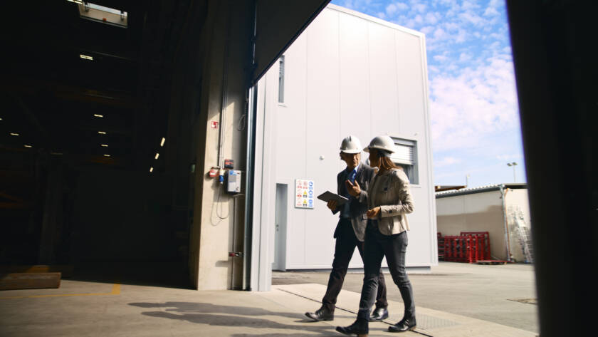 Two workers in hard hats walking under large commercial garage door
