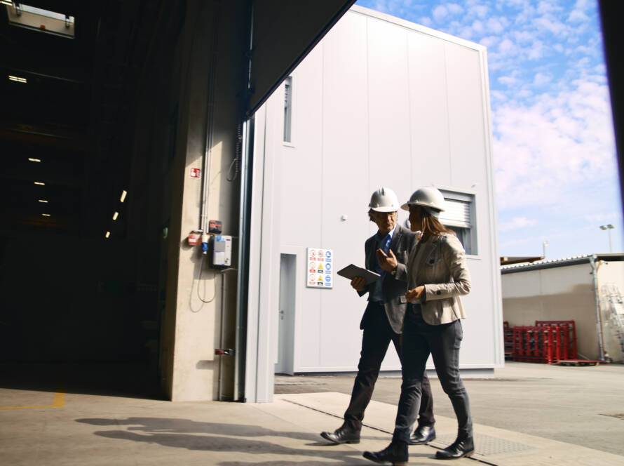 Two workers in hard hats walking under large commercial garage door