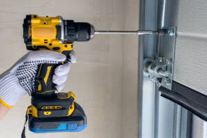 Worker drilling screw into garage door