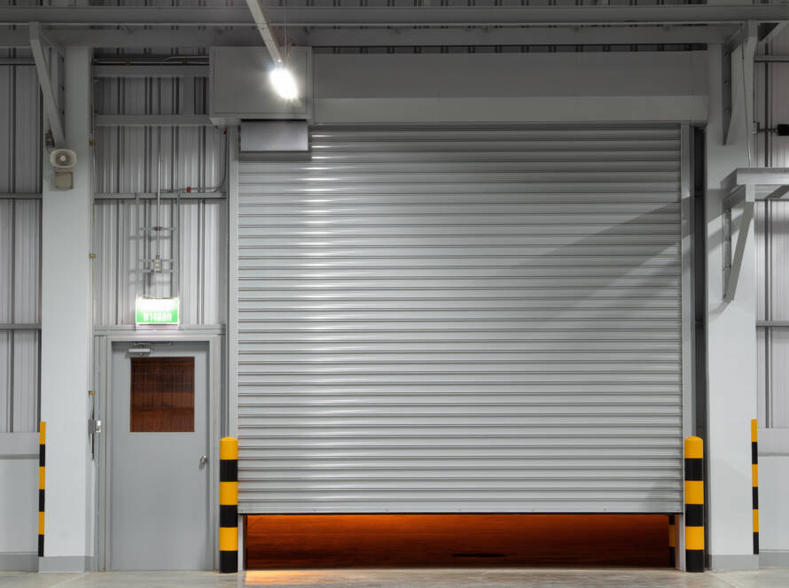 Gray commercial warehouse garage door with regular side door