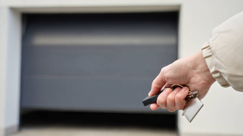 Close-up of hand holding remote and opening garage door